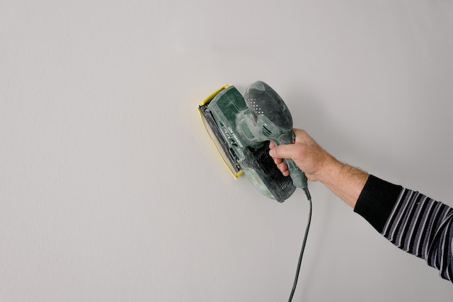 repair-service-person-using-tool-to-fix-white-wall