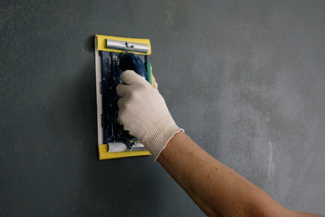 repair-persons-hand-holding-wall-sander-fixing-black-wall
